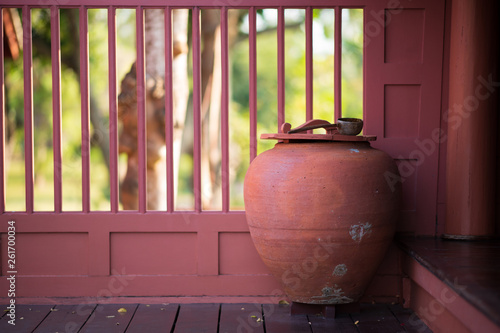 Big Thai clay Water jar on wooden floor in thai house style.