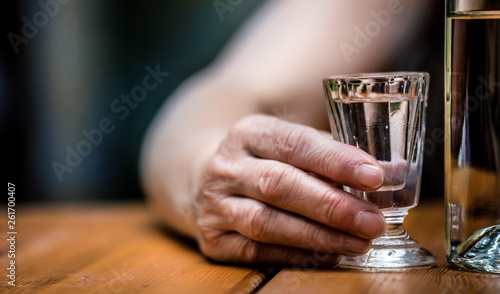 A woman sits at a table with a glass of alcohol. Concept of alcoholism.