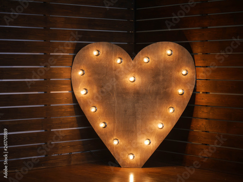 wooden heart with light bulbs on the contour on the background of wooden boards. in the studio. horizontally