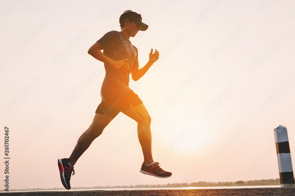 young man runner running on running road in city park