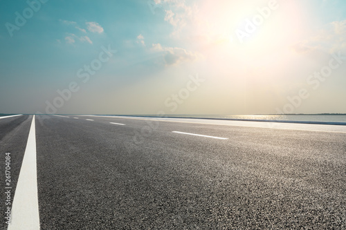 Empty asphalt road and blue sea with sky background