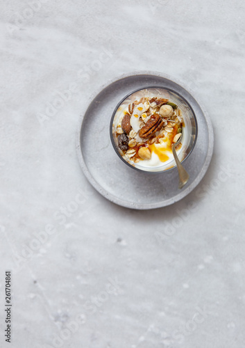 Granola with yogurt, honey and chocolate bars on marble table with copy space
