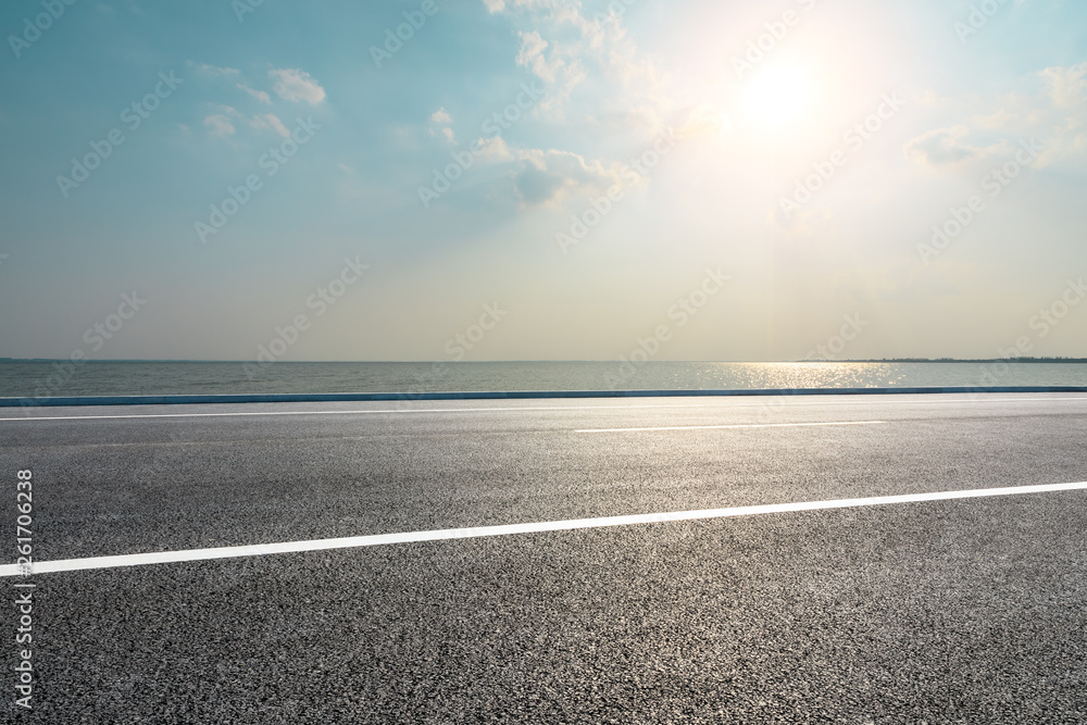 Fototapeta premium Empty asphalt road and blue sea with sky background