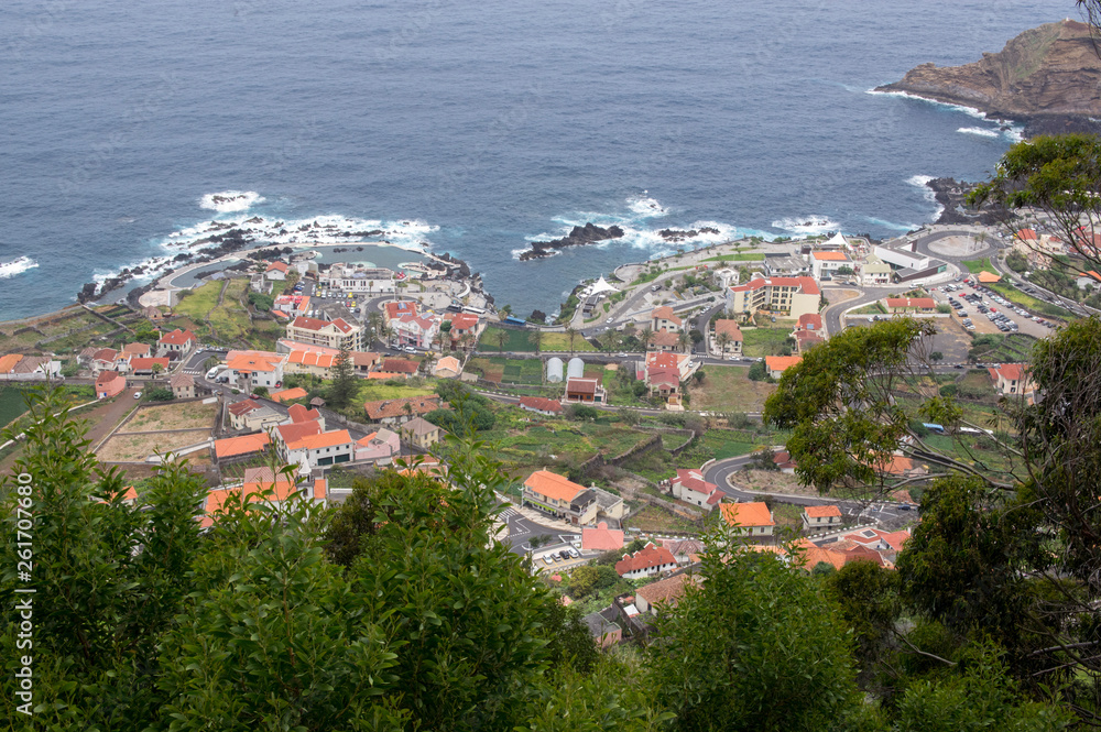 Madeira island, town Porto moniz aerial view, houses and hotels, coastline with rocks and beautiful greenery