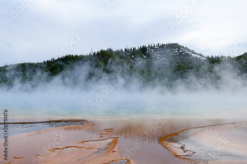 colorful lake in yellowstone with mountain background and blue sky
