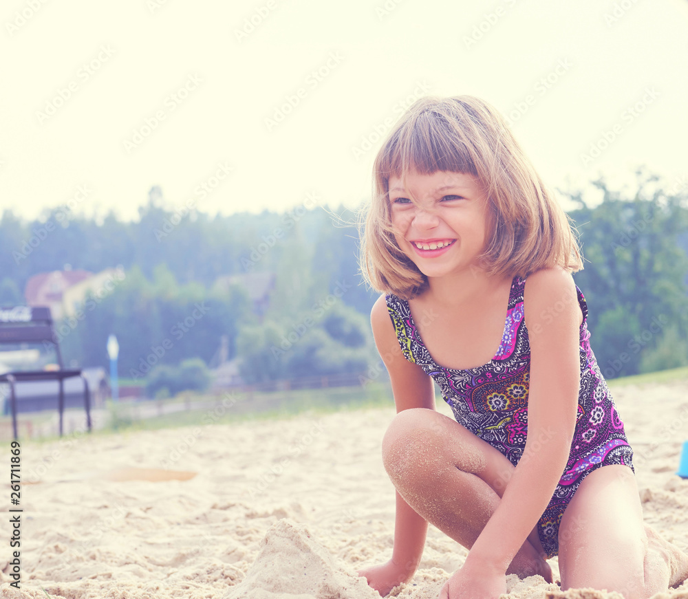 Cheerful happy little girl playing with send at beach enjoying nature -  freedom concept. Resting outdoors enjoying sunny day at ocean ore lake  beach. Stock Photo