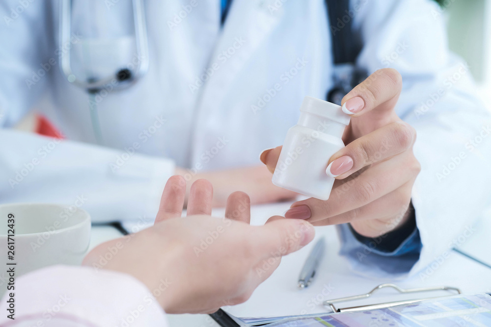 Female doctor hands gives jar of pills to patient hand closeup. Female doctor hands gives jar of pills to patient hand closeup.