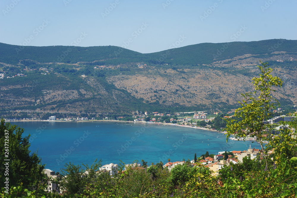 Mediterranean seascape: cozy town with old stone houses red roofs and mountains background.