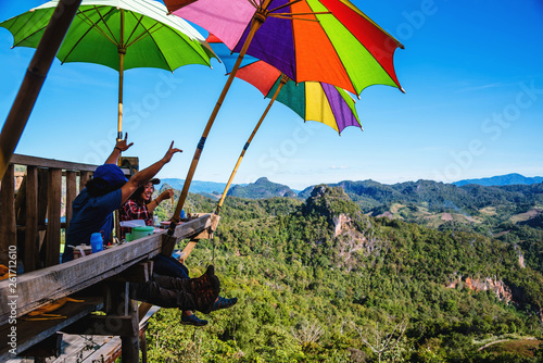 Tourists asian couple sitting eat noodle on the wooden platform and looking scenic view of beautiful nature mountains at Ban Jabo,Mae Hong Son, Thialand.