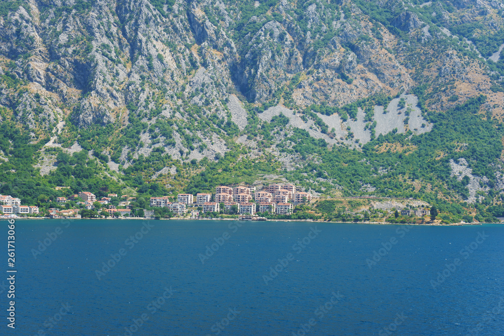 Mediterranean seascape: cozy town with old stone houses red roofs and mountains background.