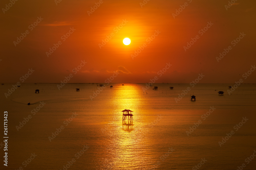 golden sunrise skyline with silhouette hut in seascape