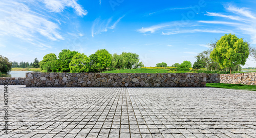 Rough square stone floor and green woods with sky background