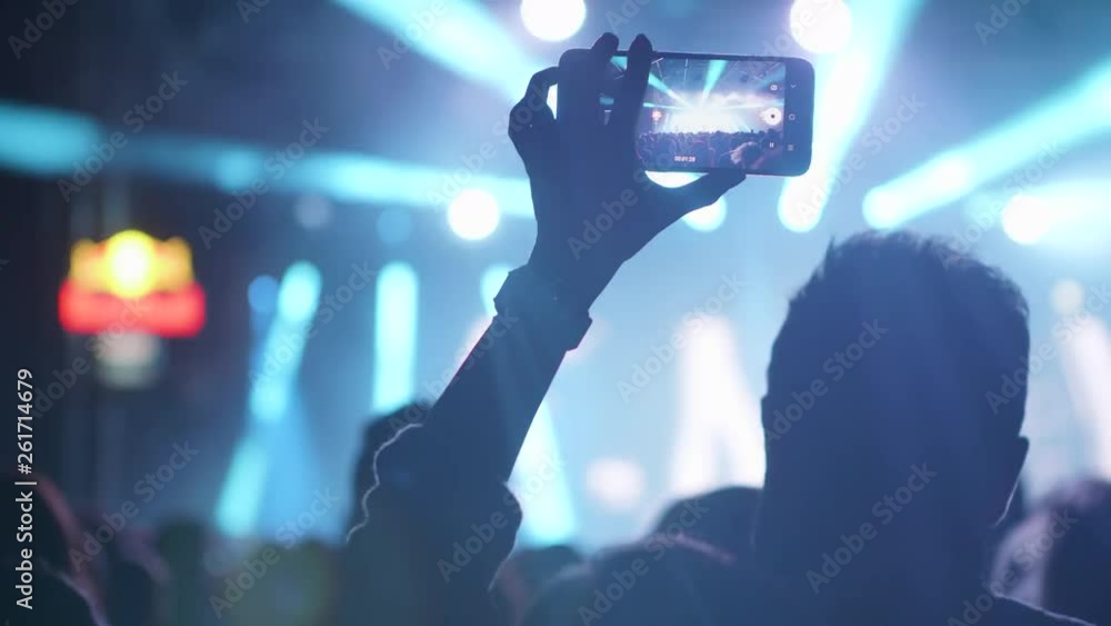 Filming on smartphone a very dynamic and bright concert performance. Fan recording a memory from a rock event. Filming on smartphone a very dynamic and bright concert performance. Fan recording a memory from a rock event.