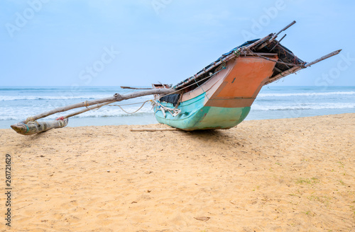 A traditional wooden fishing boat on the sandy beach with sea in the background photo