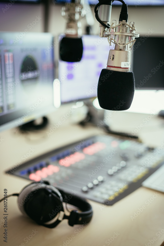 Radio broadcasting studio: Microphone in the foreground, modern studio in the blurry background