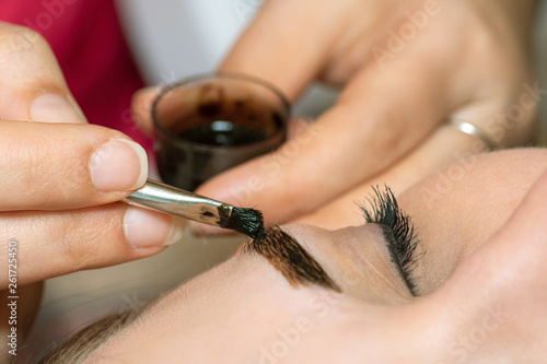 Young woman having professional eyebrow correction procedure in beauty salon