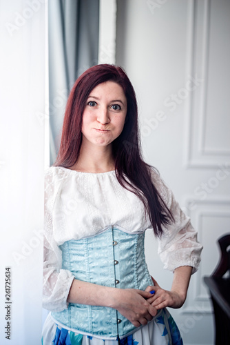 Free Download young caucasian funny woman in a sky blue corset and white shirt ready for historical ball dance - GFXLoad