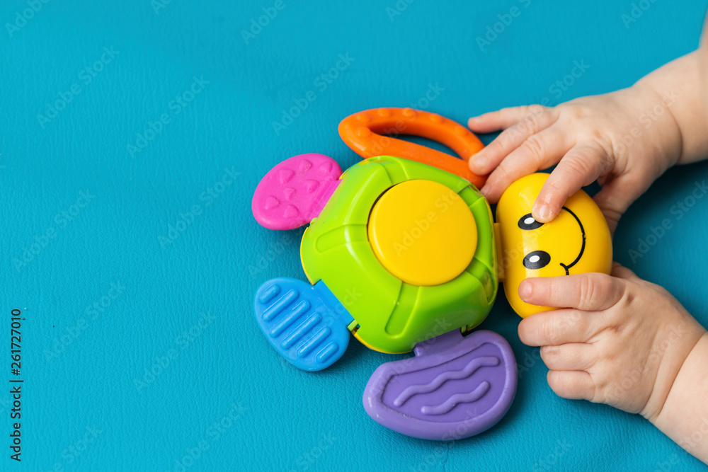 Toddler's little hands (new born) hold a toy bug with a smile on a blue background. Aquamarine. Close-up. Copy Spase Toddler's little hands (new born) hold a toy bug with a smile on a blue background. Aquamarine. Close-up. Copy Spase