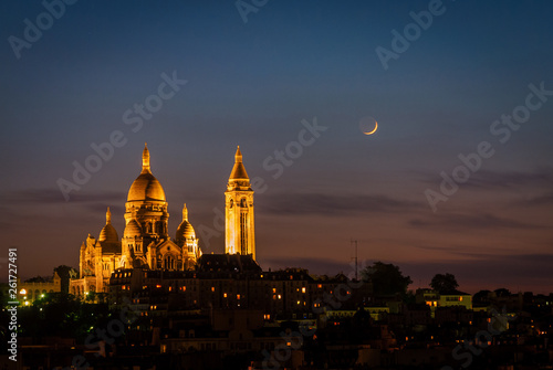 Illuminated Sacre Coeur Basilica and moon at night in Paris