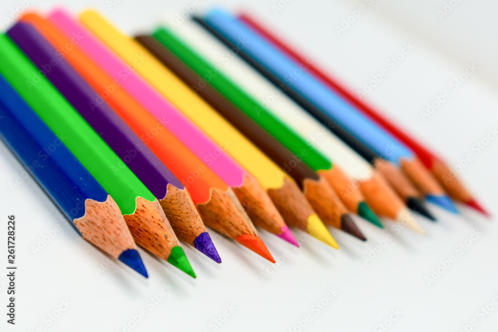 Close-up of a selection of Multi Colored pencils crayons, stick together arranged in a row line bar graph on white background, flat lay. Selective focus, blur image. Back to school creativity concept. Close-up of a selection of Multi Colored pencils crayons, stick together arranged in a row line bar graph on white background, flat lay. Selective focus, blur image. Back to school creativity concept.