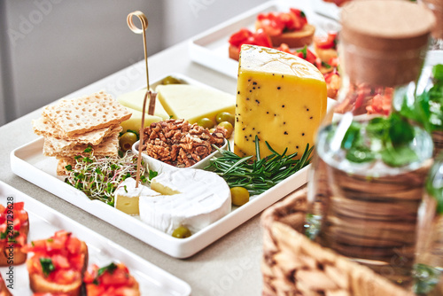 Appetizers table with antipasti snacks. Cheese and meat variety board over bright table 