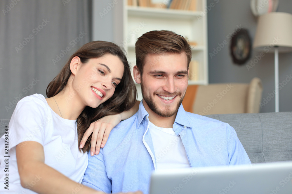 Young couple doing some online shopping at home, using a laptop on the sofa. Young couple doing some online shopping at home, using a laptop on the sofa.