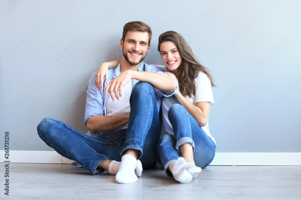 The happy couple sitting on the background of the gray wall. The happy couple sitting on the background of the gray wall.