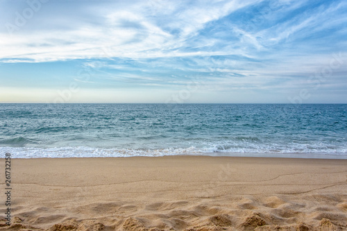 The beautiful view of the sandy ocean beach with bright blue cloudy sky