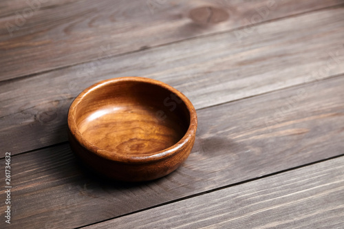 Empty wooden bowl on brown table. Round salad-bowl