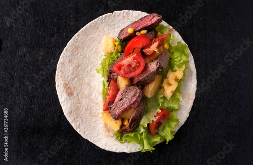 Cornbread with beef, vegetables and pineapples and corn grains on a wooden kitchen Board. Food preparation. Taco al pastor on a black wooden Board. Top view with copy space