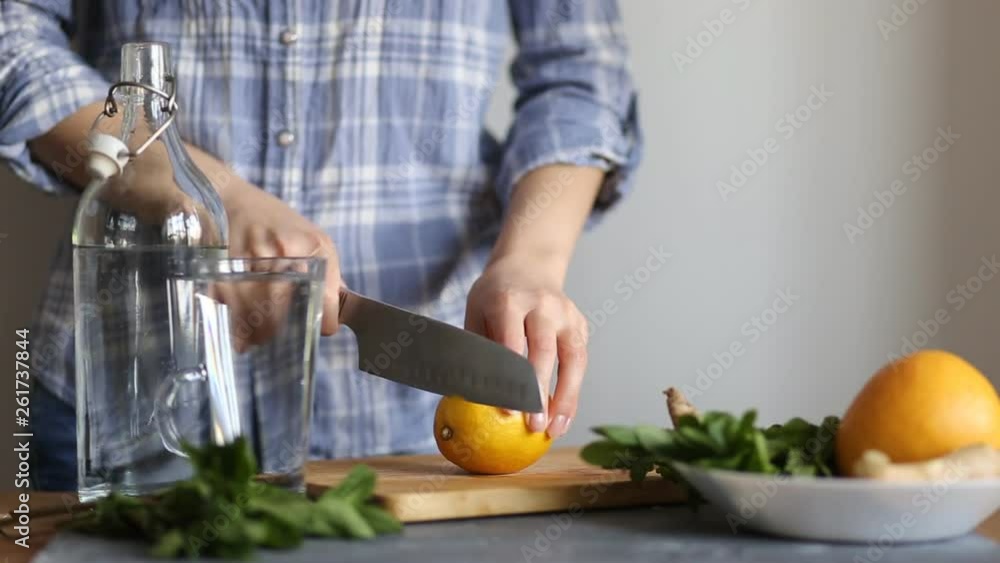 Closeup of a woman cutting a yellow ripe lemon with a knife on a wooden Board in the kitchen Closeup of a woman cutting a yellow ripe lemon with a knife on a wooden Board in the kitchen