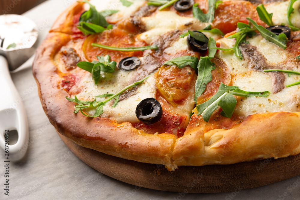 Pizza con mozzarella, pomodoro, acciughe, rucola e olive nere