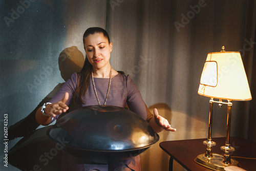 Young woman playing on a first generationan instrument called '' Hang '' or ''Hang drum'' photo