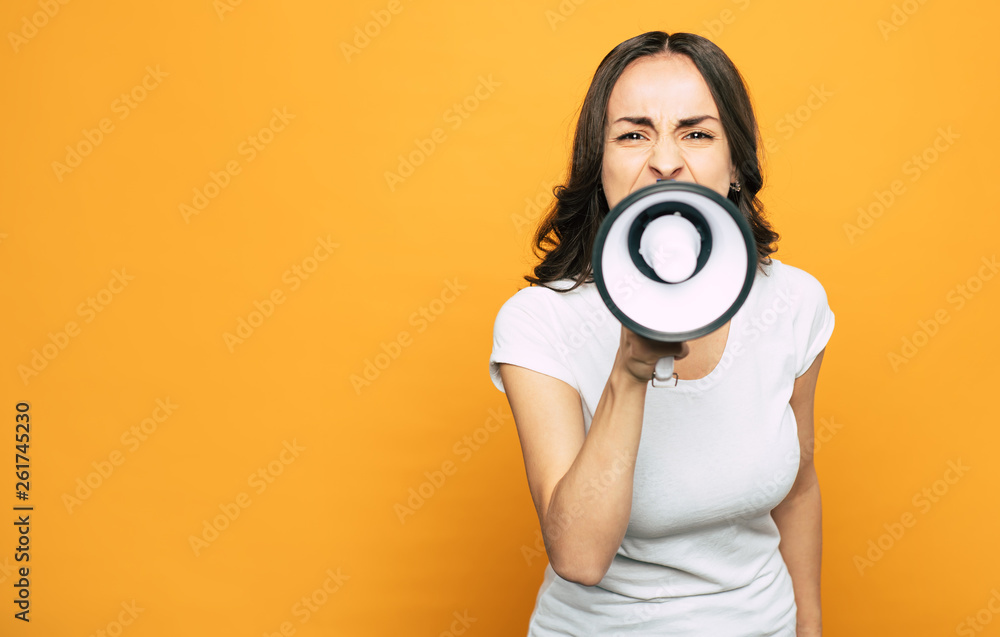 Obraz premium Screaming bloody news. A girl who is screaming right into the megaphone with her face full of negative emotions next to the camera.