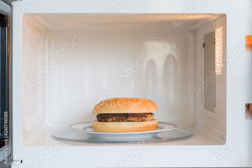 Unappealing microwavable hamburger on a plate in a microwave oven photo