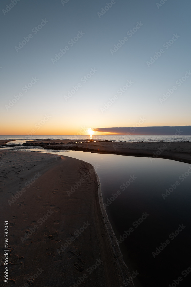 Fototapeta premium Red vivid sunset at the Baltic Sea with mirror like water - Veczemju Klintis, Latvia - April 13, 2019