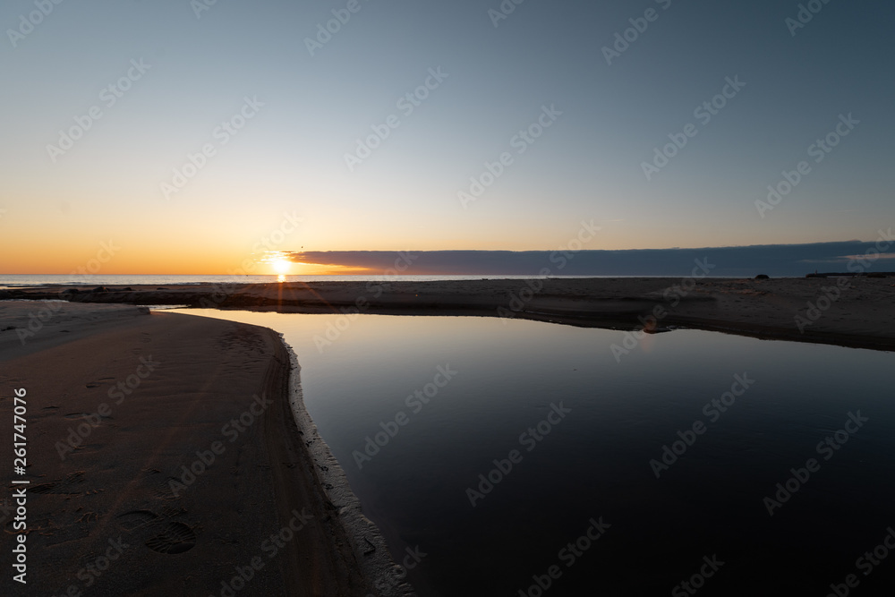 Fototapeta premium Red vivid sunset at the Baltic Sea with mirror like water - Veczemju Klintis, Latvia - April 13, 2019