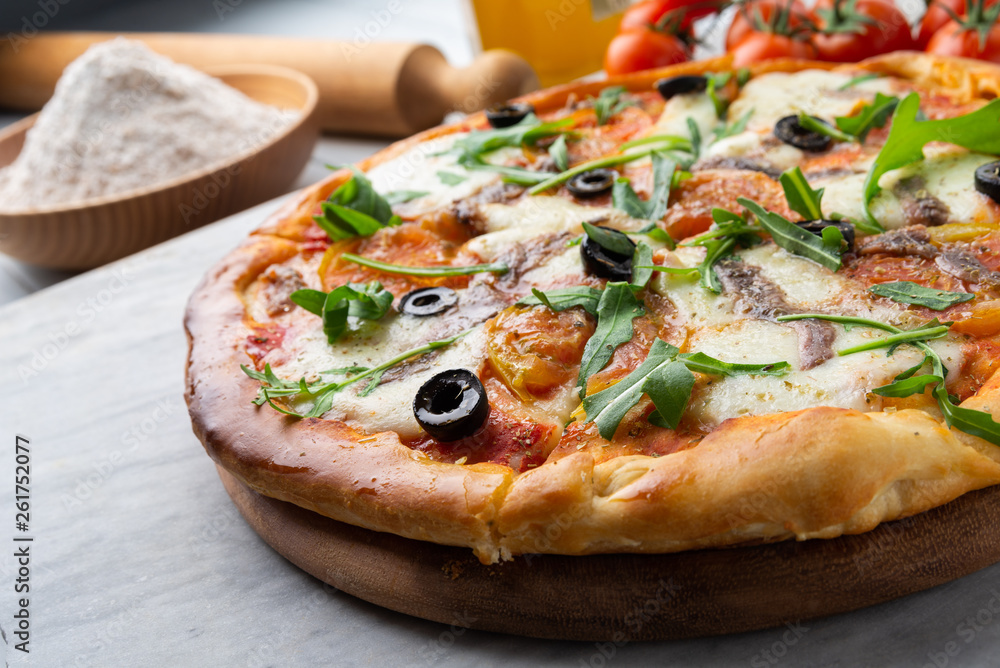 Pizza con mozzarella, pomodoro, acciughe, rucola e olive nere Pizza con mozzarella, pomodoro, acciughe, rucola e olive nere