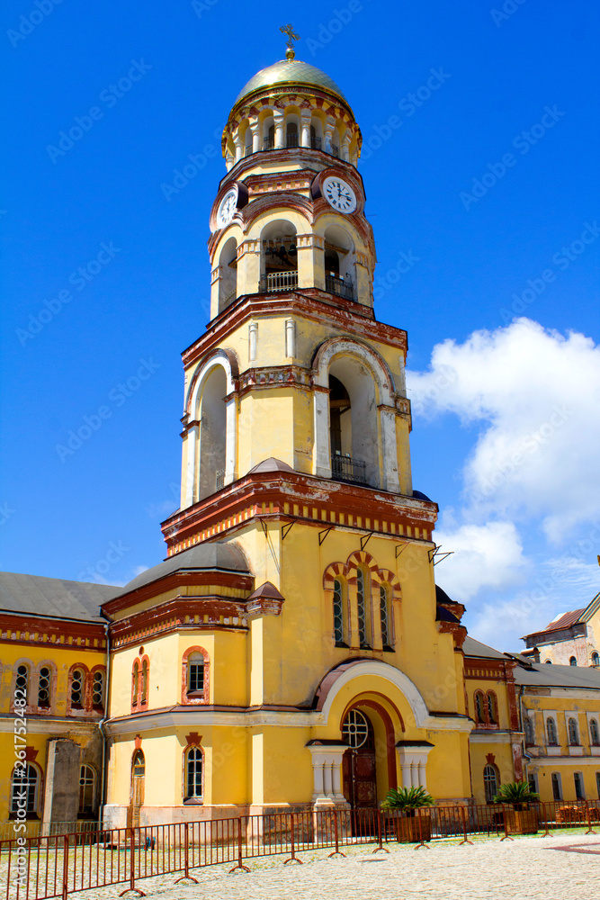 Yellow tower of the church with a golden dome and clock