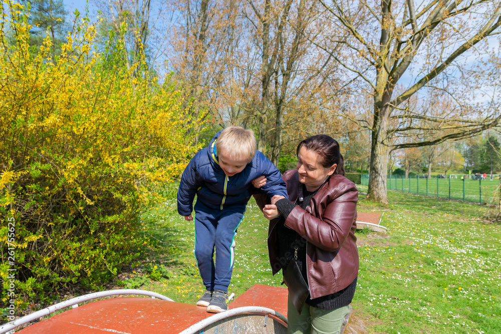Defect,childcare,medicine and people concept: Happy mother and son with down syndrome playing together in a park at spring time. Defect,childcare,medicine and people concept: Happy mother and son with down syndrome playing together in a park at spring time.