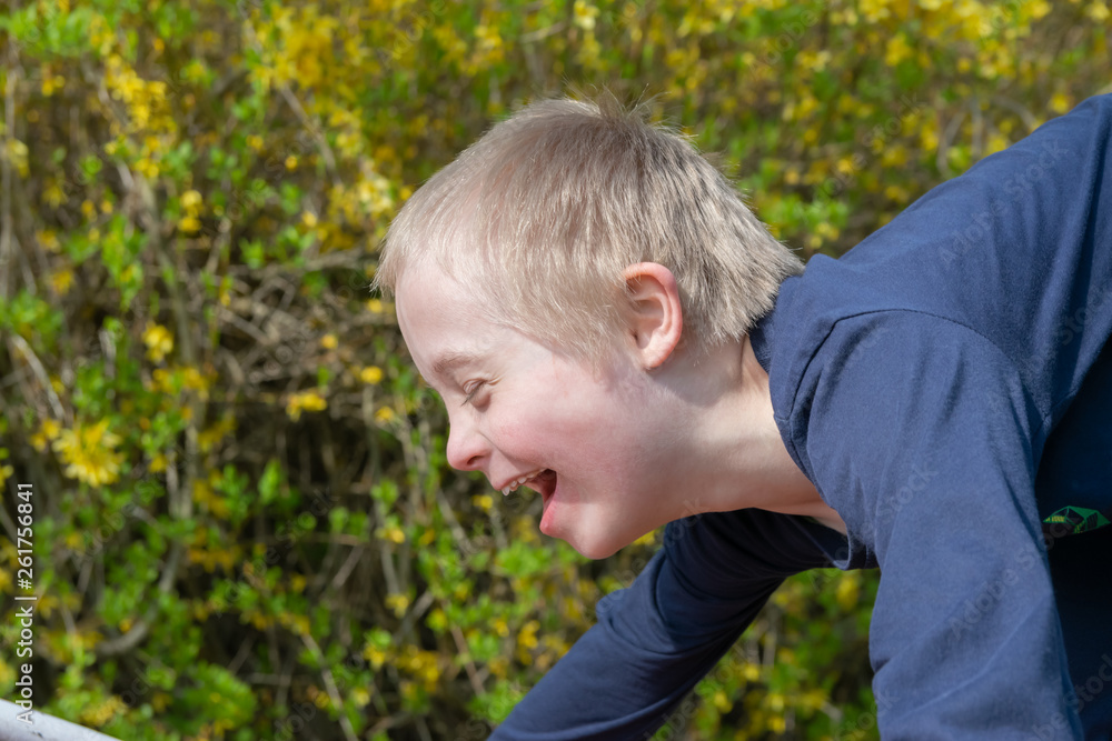 Defect,childcare,medicine and people concept: Blond boy with down syndrome playing in a park at spring time. Defect,childcare,medicine and people concept: Blond boy with down syndrome playing in a park at spring time.