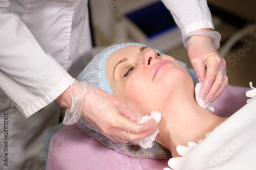 Cosmetologist remove a face mask to her patient . Anti-ageing and smoothing procedure in a beauty salon. Doctor in a cosmetological clinic making a treatment of skin care