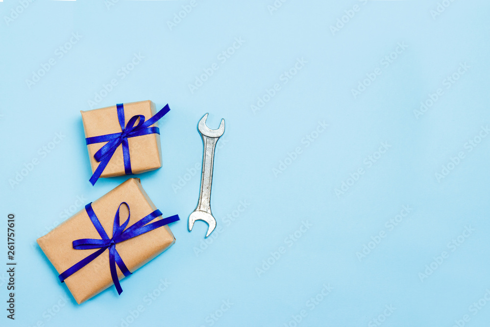 Father's day concept card with man's work tool on blue background and gifts boxes wrapped in kraft paper and tied with blue bow. Top view.