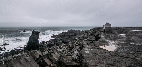 Icelandic black rock coast with moody weather and asian girl in background