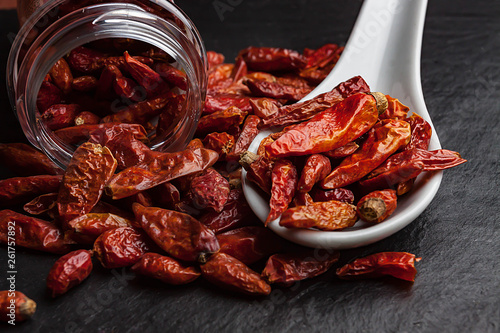 CLOSE UP OF SPICY CHILIES IN SPOON AND GLASS JAR