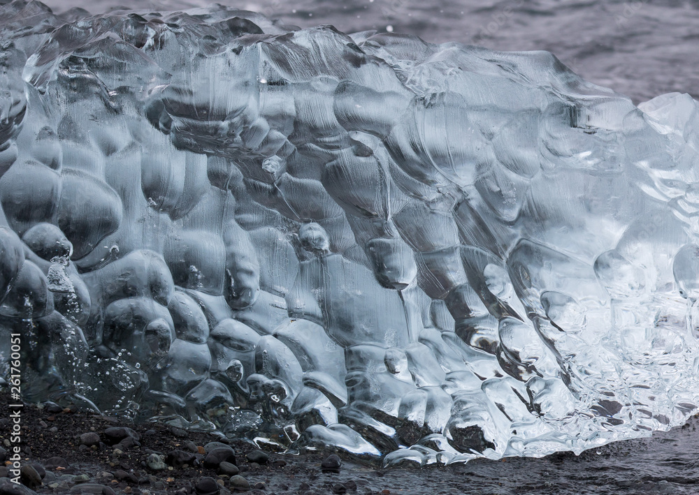 Obraz premium Amazing transparent blue iceberg pieces on Diamond beach with black sand near Jokulsarlon lagoon, Iceland. Ice calving. Black and white contrast.