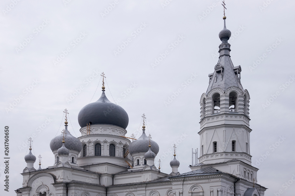 Christian orthodox white church with silver and grey domes with gold crosses. Calm grey sky above Christian orthodox white church with silver and grey domes with gold crosses. Calm grey sky above
