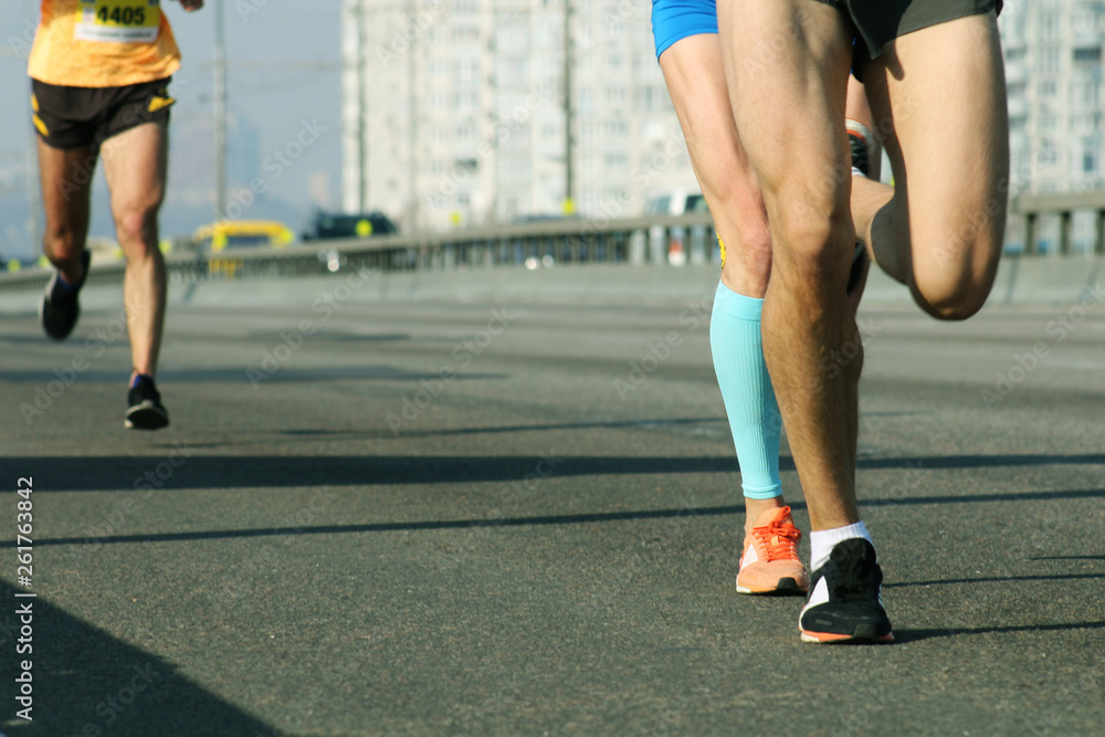 Marathon running in the light of morning. Running on city bridge detail on legs Marathon running in the light of morning. Running on city bridge detail on legs