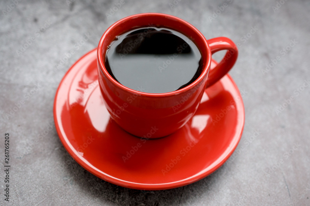 Red cup of coffee on a saucer on a black background