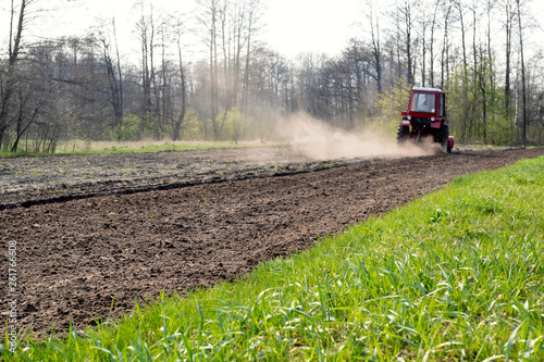 Red tactor plows field in spring. photo